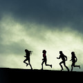 silhouette of four woman running reflected in water silhouette of four woman running reflected in water
